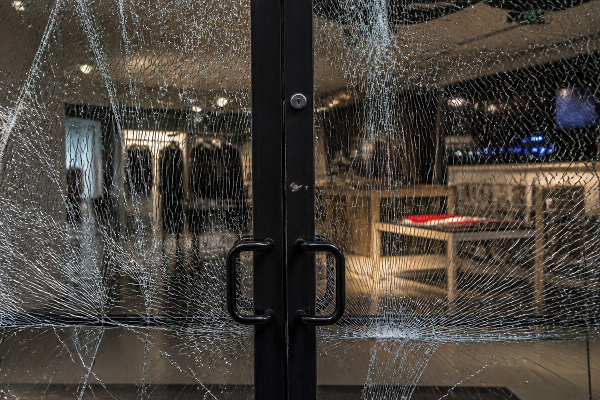 Shattered storefront glass door held intact by 3M security window film